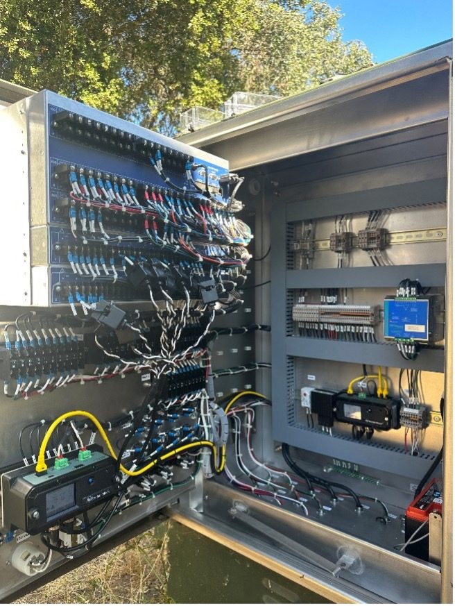 An open electrical switchgear cabinet fully wired for commissioning at a field site