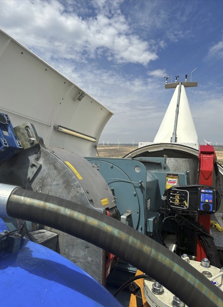Technician's view inside an open wind turbine nacelle, showing the gearbox, generator, and hub