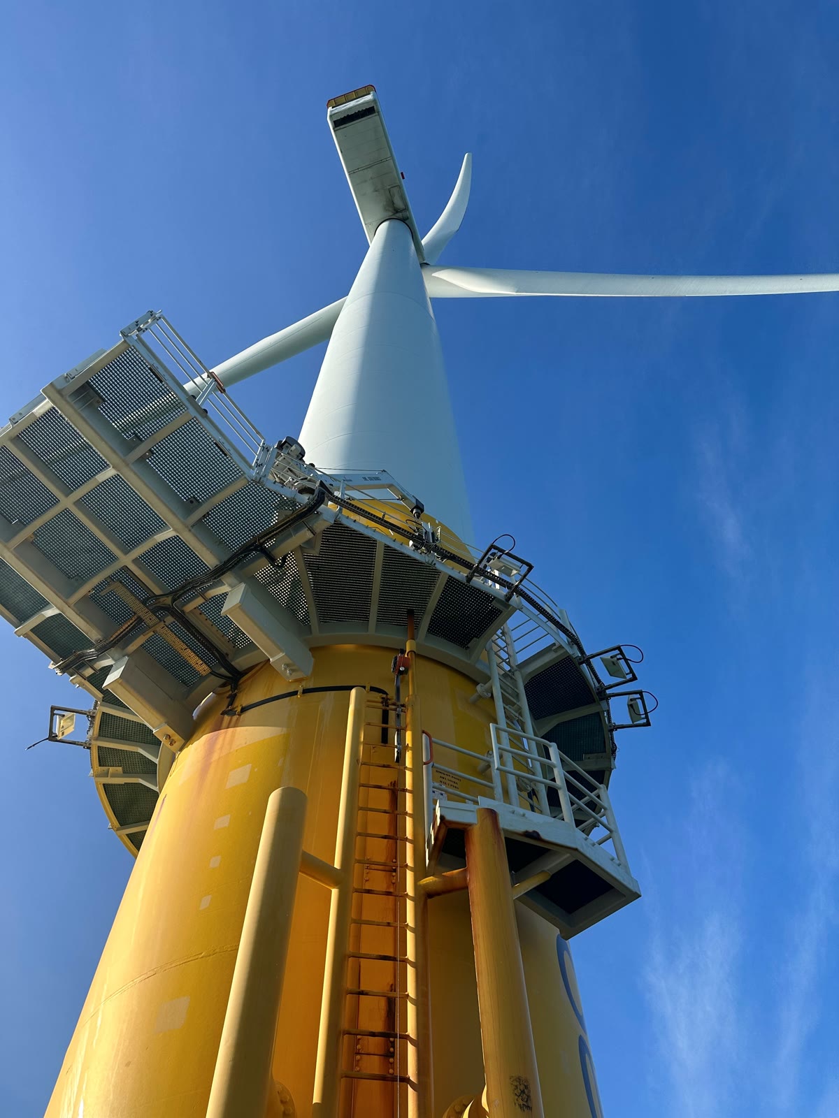 Wide-angle view of an offshore wind turbine's monopile base and nacelle access platform